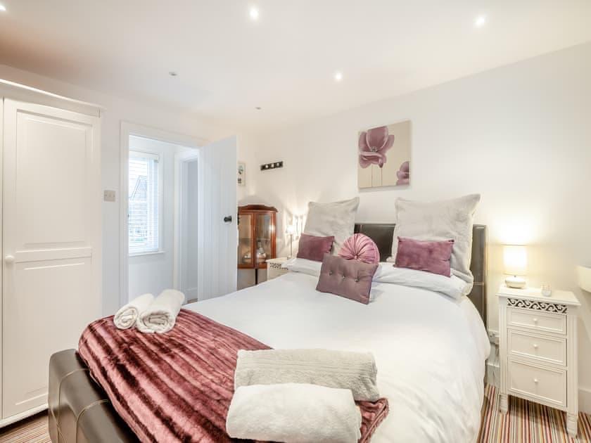 Bedroom one, with a plum and grey colour scheme and a dark leather headboard
