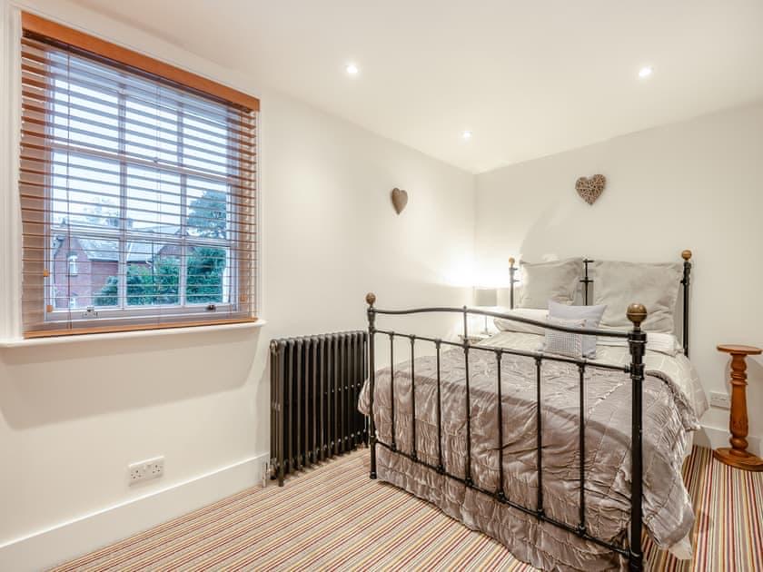 Bedroom two, with a black wrought-iron bed frame beneath a shuttered window