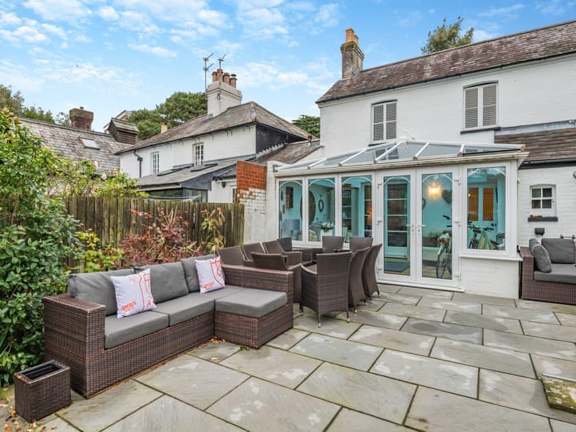 Garden patio with outdoor seating, dining furniture and the cottage behind