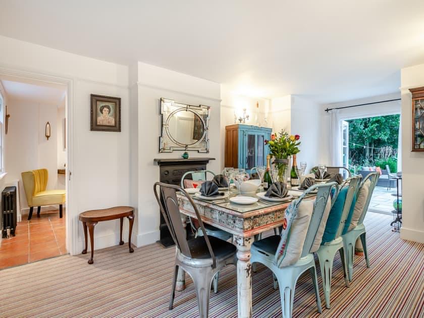 Dining room with a large table set for eight, opening through to the sitting room and garden