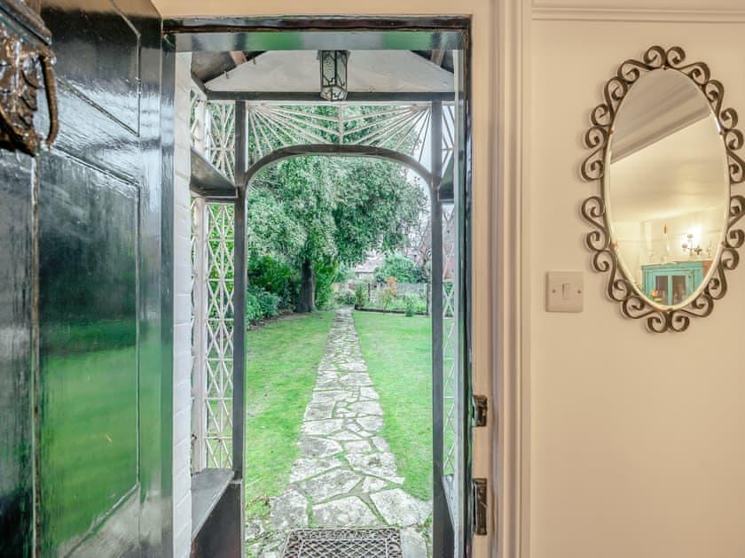 The front door open onto a stone path leading through the garden