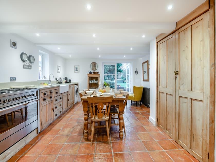 Farmhouse kitchen with a range cooker, wooden table and doors opening onto the garden