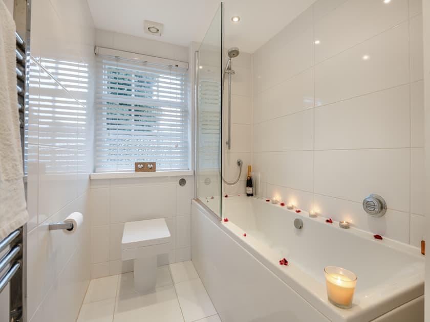White tiled bathroom with a bath styled with candles